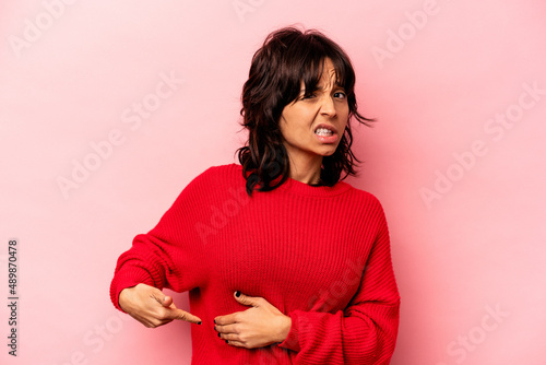 Young hispanic woman isolated on pink background having a liver pain, stomach ache.