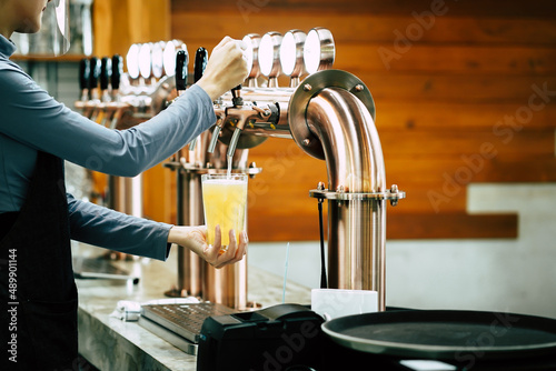 Close up bartender hand pour draft beer to glass from beer tap in pub or restaurant