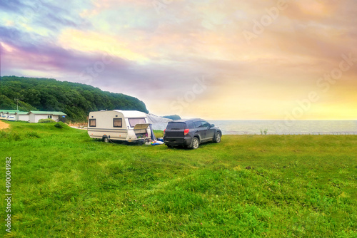 Mobile home, tent and car at sunset. Tourist camp by the sea, lake. Trailer