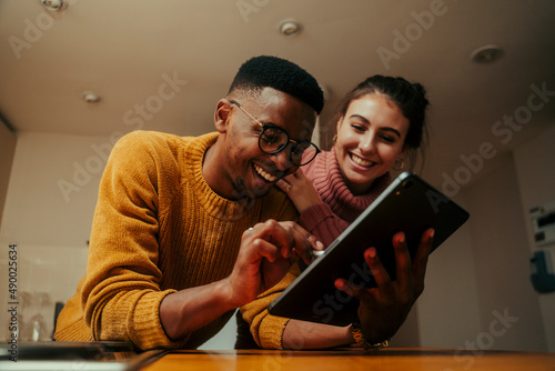biracial couple working from home typing on digital tablet