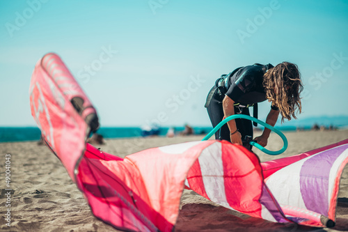 Woman preparing kiteboarding kite with the air pump