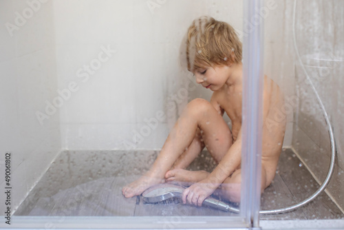 Blond child, sweet toddler boy in bathroom, taking shower, sitting on the floor, punished