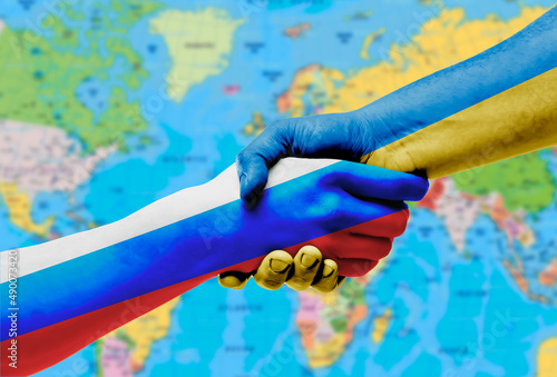The flags of Ukraine and Russia shake hands on the background of the world map.