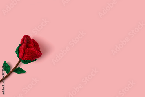 Beautiful red rose on a pink background on one side with room for text. Handmade crochet and wool rose. Amigurumi design