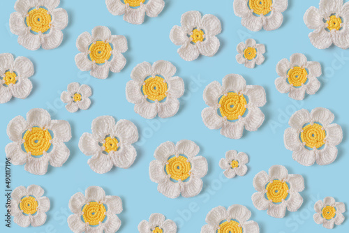 Beautiful white daisies made by hand in crochet and wool. Daisies pattern on blue background. Amigurumi design