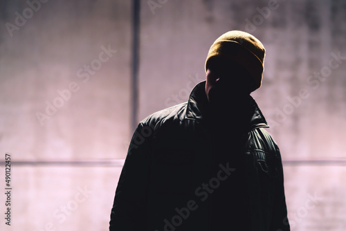 Man with dark face. Unknown stranger, stalker, thief or gangster in shadow. Secret hidden identity of mysterious person. Dangerous criminal in jacket. Handsome anonymous male fashion model in portrait