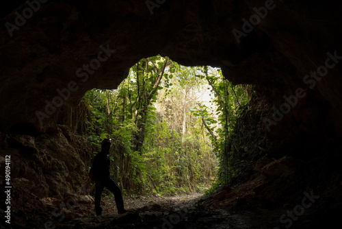 Male speleologist with a helmet exiting the dark cave after studying it