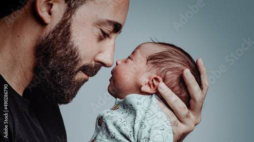 portrait of man looking at his newborn son with loving expression