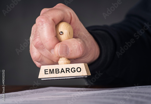 Hand with stamp and inscription embargo stamps a document