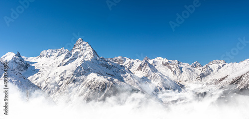 Panoramic view of winter snowy mountains in Caucasus region in Russia with blue sky