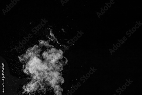 Curly white steam rising up and splashing water scattering in different directions isolated on a black background. Evaporation of liquid and condensation. Can be used as background, design element