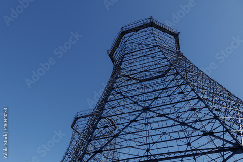 Uprisen angle view of former gasometer, existing structure against blue sky. 