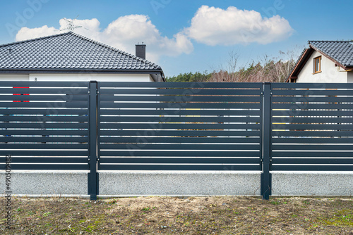 Modern anthracite panel fencing, visible spans and a fence foundation connector, view from the garden.