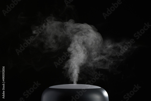 The concept of humidification of the air. Photo with copy space. Modern air humidifier on black background.