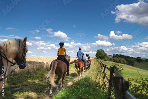 Reiterferien - Ausritt durch eine idyllische Landschaft im Sommer - vorbei an einem reifen Getreidefeld