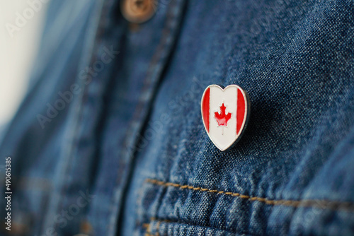 Canadian flag icon is pinned on blue jeans jacket. Canada patriotism concept.
