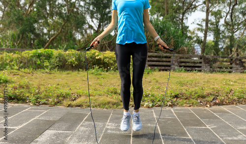 Asian woman skipping rope in park