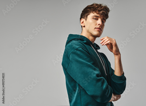 Handsome man in green hoodie isolated on gray background