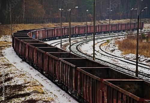 Stare sterane , zardzewiałe wagony pociągu towarowego stojącego na bocznicy w lesie , w zimie,posypane śniegiem