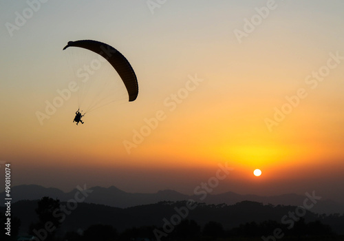 Beautiful shot of a human paragliding during sunset at Bir, Himachal Pradesh, India