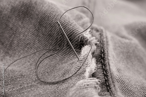 Hole in jeans. Needle with thread for darning jeans. Tools for work dressmaker, seamstress fashion designer