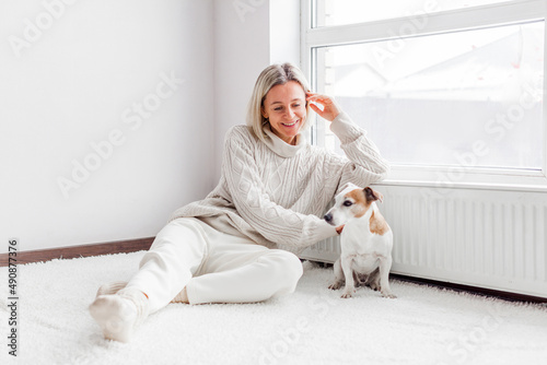 serene adult woman with dog near radiator in the living room at home