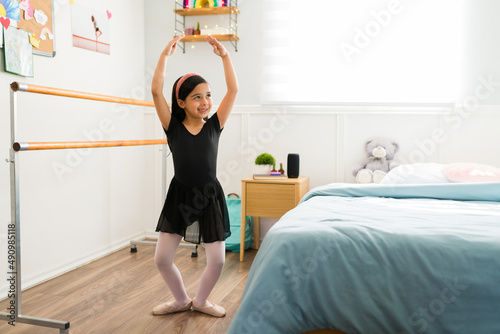 Cheerful elementary girl dancing in the bedroom