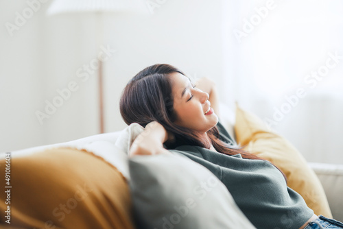 Closeup - Relaxed young asian woman enjoying rest on comfortable sofa at home, calm attractive girl relaxing and breathing fresh air in home, copy space.