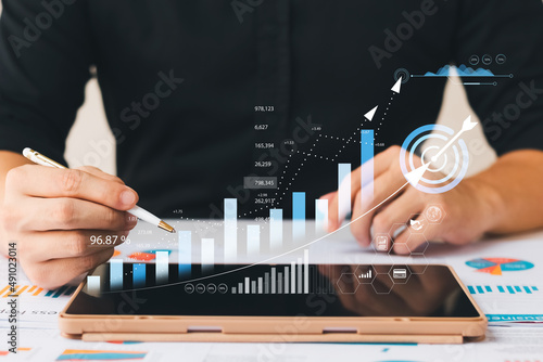 Businessman analyzing company's financial balance sheet working with digital augmented reality graphics. Businessman calculates financial data for long-term investment.