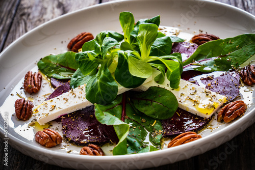 Beetroot carpaccio with goat cheese and pecan nuts on wooden background 