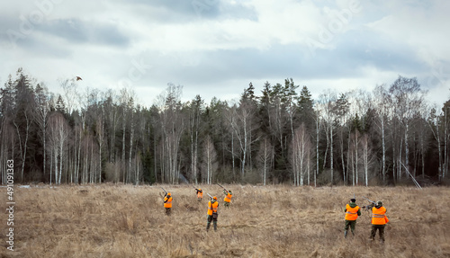 A group of hunters hunt pheasants. Hunters in camouflage uniforms with weapons and dogs went hunting
