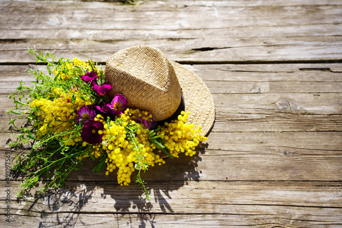 straw hat with mimosa flowers on wooden table. women's day