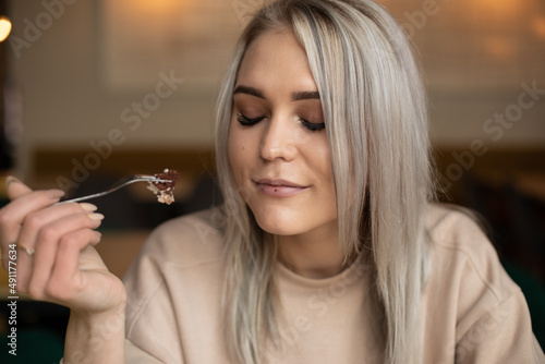 Blond smiling enjoying woman, with make up, closed eyes with pleasure, tasting delicious cake. Restaurant business, 