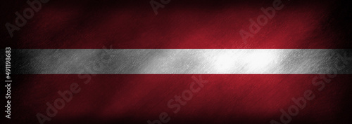 The Latvian flag on an old looking background