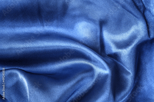Elegant smooth blue silk or satin folds closeup. Cloth texture background. Abstract wallpaper. Trendy dark skyblue backdrop for web design. Luxury twisted fabric backplate 