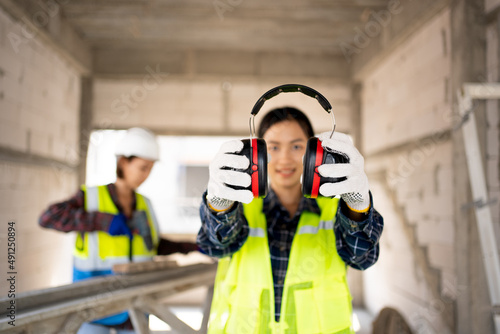 Pretty Asian Engineer,foreman Campaign to wear soundproofing equipment.Recommendations for wearing ear muffs. Work safely with noise reduction. a young woman using an electric screwdriver safely.