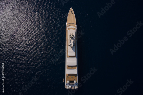 Big yacht for millionaires in the sea drone view. Luxurious white mega yacht on dark water in the reflection of the sun top view. Big white super ship in the dark ocean aerial view.