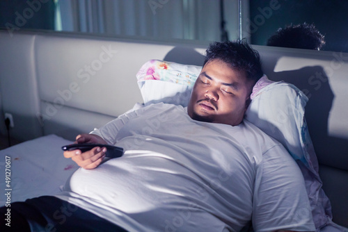 Obesity man falls asleep while watching TV at home