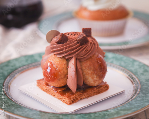 Close up of traditional French pastry called "Saint-Honoré" with cream chocolate mousse and puff-pastry. Coffee in background. A dessert named for the French patron saint of bakers and pastry chefs