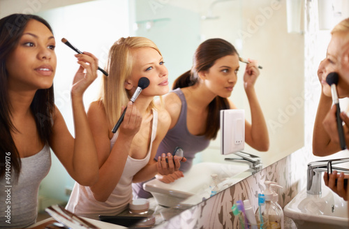Beauty Queens. Shot of three friends applying makeup in front of the mirror.