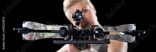 Young woman shooting with crossbow isolated on black background.