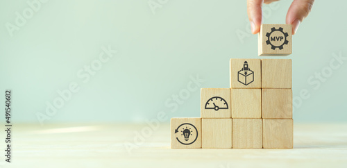 MVP, minimum viable product concept for lean startup. Life cycle of product development. Analysis and market validation. Hand puts wooden cubes with abbreviation MVP and learn, build, measure icons.