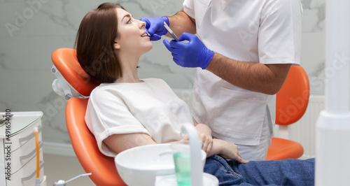 Professional dentist selects the color tone of the teeth for the female patient in the dental clinic