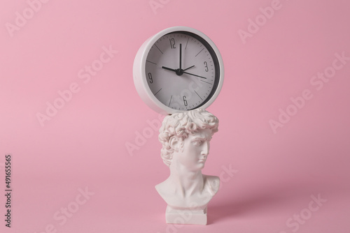 Antique David bust with clock on pink background. Conceptual pop. Minimal still life. Creative idea