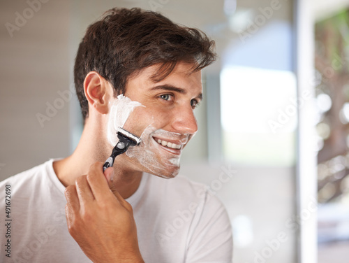 Enjoying his morning routine. Cropped shot of a young man shaving his facial hair with a disposable blade.