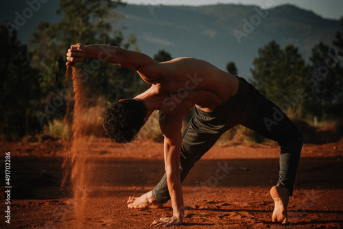 Young dancer performing and playing with red sand ground in the mountains