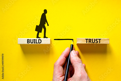 Build trust symbol. Concept words Build trust on wooden blocks on a beautiful yellow table yellow background. Businessman hand. Business and build trust concept, copy space.