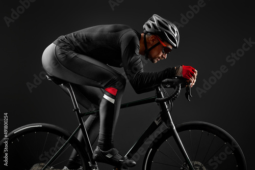 male cyclist riding road bicycle on black background