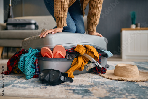 Woman trying to close overload travel suitcase