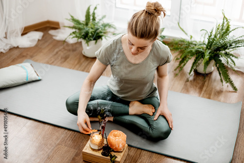 Young relaxed woman doing yoga at home with candles and incense